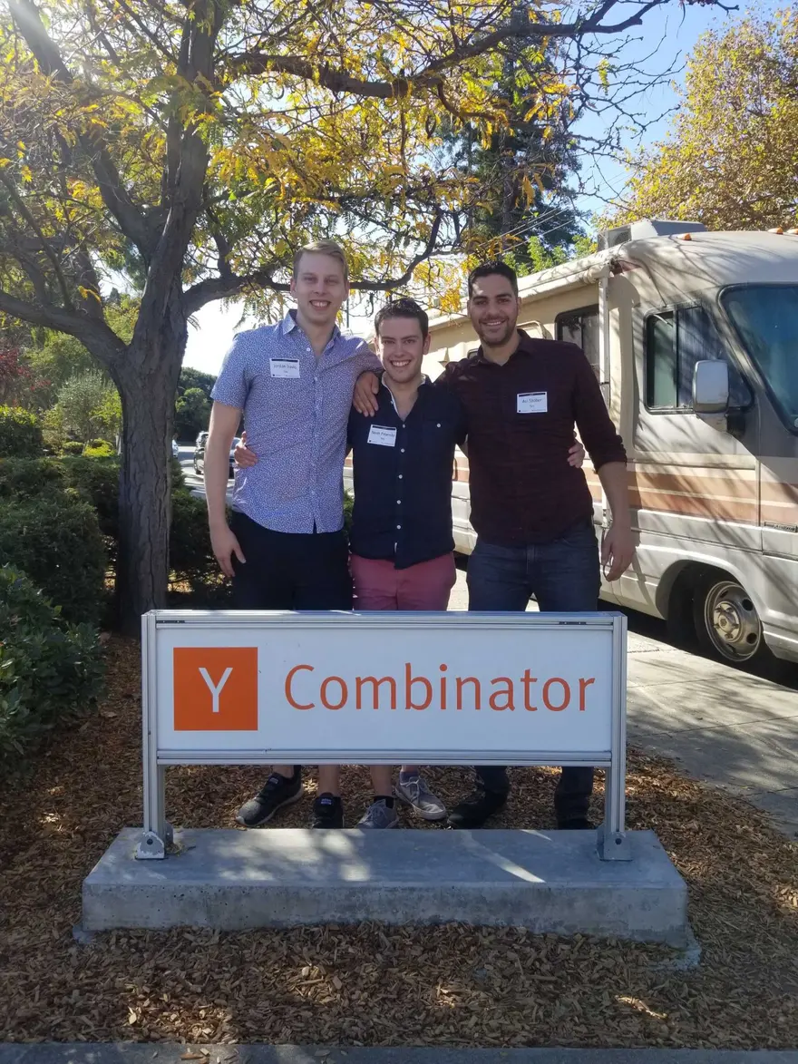 Taiv's three co-founders at the Y Combinator sign